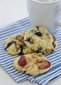 Blue Prints: Soft cookies with berries and nuts on blue and white striped napkin with mug of cappucino credit