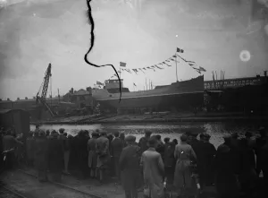 Spectators wait to see the new ship launch as the ship sits broadside on the slipway
