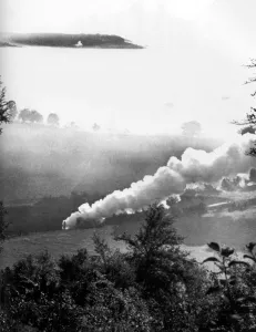 A steam train rattles through a misty valley