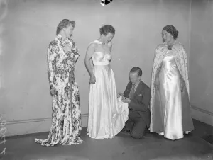 A student arranging the gowns on models for the display Exquisite gowns, designed by past
