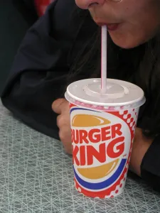Lifestyle Prints: Sucking a soft drink out of a straw in a colourful Burger King disposable cup with a plastic lid