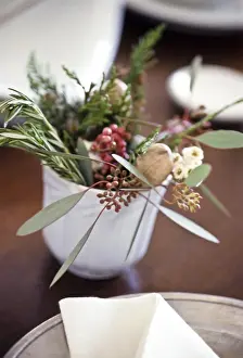 Table decoration of herbs, berries and greenery on small white cup credit: Marie-Louise