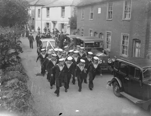 Tailors pull bridal car from church at Naval wedding in Kent village. Tailors towed