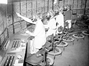 Telephone girls learn to carry on as usual in gas masks. Telephone girls are being