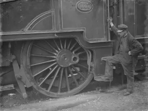 A train engineer looks at one of the large engine wheels after being derailed at Swanley