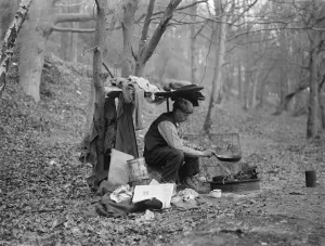 Cook Prints: Tramp at home in woods cooking food over a camp fire. 1935