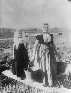 Two typical Dutch women women in native dress carrying pails. 12 August 1932