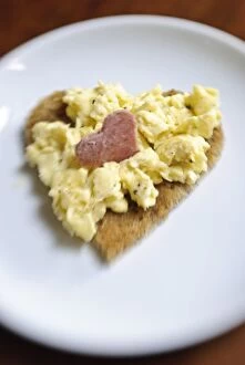 Savoury Collection: Valentines day breakfast of scrambled eggs on heart shaped toast with slice of salami