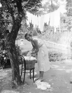 Domestic Prints: Washing day; A smiling young housewife doing the washing in a tin bath and then