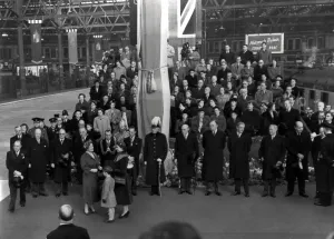 Welcome home to the the Queen Mother, with members of the cabinet in the background