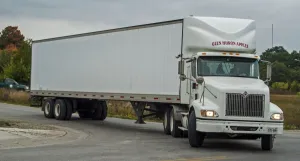 White International 6x4 semi tracter with a white twin axle box trailer turns right