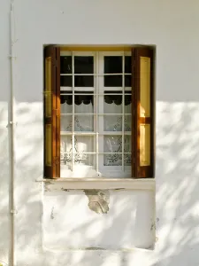Window in white house in dappled sunlight with white embroidered cutwork curtain Window in white house in dappled sunlight with white embroidered cutwork curtain