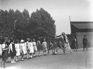 A woman playing stoolball with children in Hartley, Kent. 1937