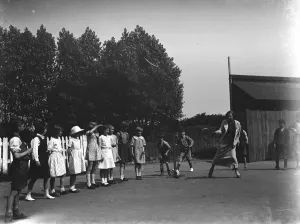 Playing Prints: A woman playing stoolball with children in Hartley, Kent. 1937