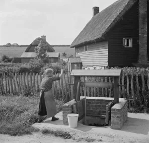 Public Transport Prints: A woman using a water well in Deans Bottom. 1936