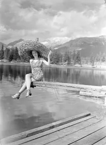 Women sits by lake in summer dress. undated