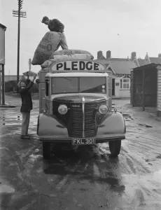 Workers are unloading sacks from a Bedford truck belonging to Pledge & Son Ltd