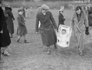 Parents Prints: A young fan being carried to the races at the R A Woolwich point to point by baby carrier