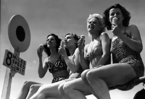 Swimsuit Prints: Four young women enjoying the sun sitting on the rails on Bournemouth sea front while