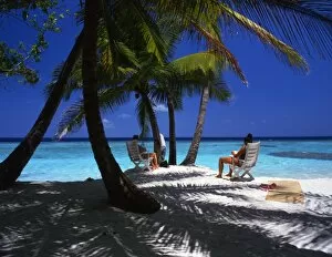 Holiday Collection: Two young women seated on a beach on the island of Bandos, in the Maldives